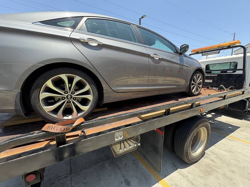 Silver sedan strapped down on the deck of a flatbed